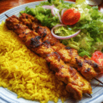 Saffron rice served with chicken skewers and fresh salad.